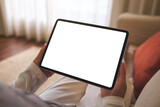 Fototapeta  - Mockup image of a woman holding digital tablet with blank desktop screen while sitting on sofa at home
