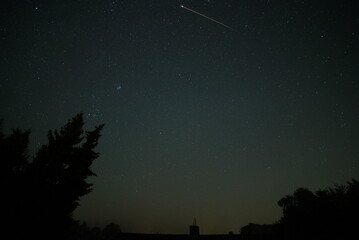 shooting star in summer in front of an illuminated city, germany