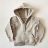 Fototapeta Sypialnia - A laid-flat beige hoodie with zipper and pockets on a plain white background, highlighting simplicity and casual wear.