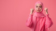 Women's Day, Hijabi women's raised hands isolated on a pink background.
