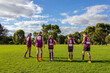 © Austockphoto - school kids walking onto football oval with afl balls seen from behind