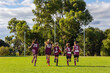 © Austockphoto - a group of kids running on a football oval seen from behind