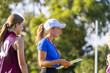 © Austockphoto - lady wearing a cap and holding a clipboard with children in sports uniforms