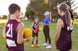 © Austockphoto - football coach talking to young kid with teammates looking on
