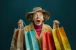 Surprised woman in hat and coat holding shopping bags with mouth wide open and shocked expression