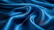   A close-up of a blue cloth features a wavy design atop its shimmering surface