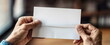 Senior person holds blank folded paper on blurry background closeup. Mature immigrant receives letter from relatives stayed in native country.
