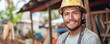 Happy Latin American man worker in helmet works at village construction site. Cheerful male immigrant new career. Work visa owner.