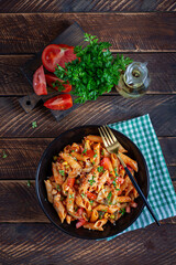 Wall Mural - Classic italian pasta penne arrabbiata with vegetables on wooden table. Penne pasta with sauce arrabbiata. Top view, overhead