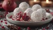   A white plate holds a pomegranate, its ruby arils peeking out from beneath a dusting of powdered sugar Another pomegranate rests atop
