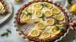   A tight shot of a pie on a plate, garnished with sliced lemons A hand holds a knife, poised to slice