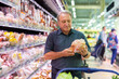 Elderly man chooses chicken meat in supermarket