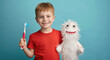 Cute smiling boy holding toothbrush and cute white knitted tooth pattern with eyes isolated on blue background, concept of children's dental health care
