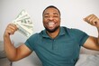 Black guy sitting on a couch in living room holding a cash