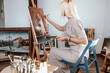 Young, blonde woman painting in her atelier