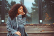 Outdoor autumn photo of young thoughtful african american woman sitting on wooden stairs on fall day