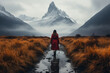 Nature, states of mind, travel concept. Woman with red coat walking on dirty path between dry meadow toward the mountains which are covered with clouds
