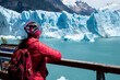 Turista mujer con campera roja mirando el Glaciar Perito Moreno, desde las pasarelas del Parque Nacional Los Glaciares	