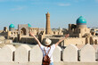 Panoramic view of Bukhara, young woman tourist with arms raised in front of Bukhara city - Uzbekistan