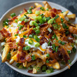 A high-angle shot of a plate of fries topped with melted cheese, bacon bits, green onions, and sour cream, resembling loaded potato fries.
