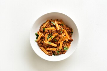 Canvas Print - Penne pasta with minced meat, tomato sauce and greens. Top view, flat lay