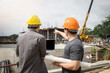 © skarie - Team of construction workers discussing project details with blueprint in construction site.