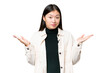 Young Asian woman over isolated chroma key background making doubts gesture