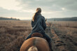 Person rides horse across autumn field, back view. Horseback riding in nature