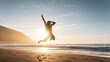 Happy man with backpack jumping with arms raised on the beach at sunset - Charming tourist enjoying summer vacation by the sea - Traveler lifestyle and wellness concept