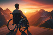 A man in a wheelchair on top of a mountain contemplating the sunset