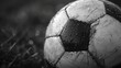 Close-up shot of a traditional black and white soccer ball, focusing on the texture and stitching details, showing grass in the blurred background