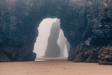 Fototapeta Morze - Playa de Las Catedrales in foggy day. Catedrais beach in Ribadeo, Lugo, Galicia, Spain. Natural archs of Cathedrals beach. Moody rock formations on misty day. Travel destination