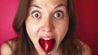 Surprised young woman holding a red pepper in her mouth