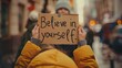 © Ilia Nesolenyi - Closeup shot of a persons hands holding a sign that reads Believe in yourself
