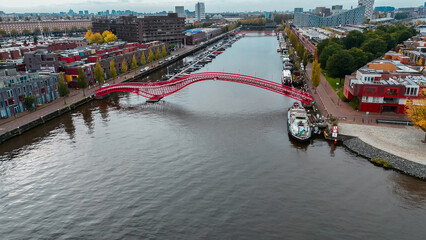 Wall Mural - Aerial drone view of modern footbridge Python Bridge at Eastern Docklands neighborhood of Amsterdam Netherlands