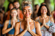 © apratim - A group of diverse people smiling peacefully while practicing yoga in a serene indoor setting.