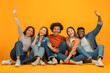 © Prostock-studio - Friends sitting and raising hands joyfully on orange background