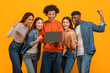 © Prostock-studio - Group looking at laptop screen excitedly on orange background