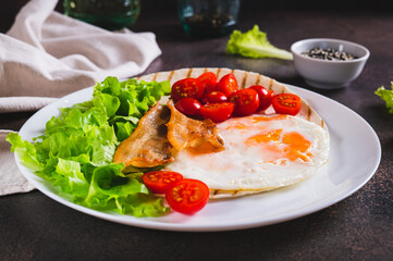 Wall Mural - Appetizing tacos with fried egg, bacon, tomato and lettuce on a plate on the table