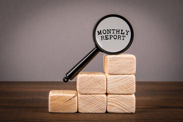 Wall Mural - Monthly Report Concept. Magnifying glass and wooden blocks