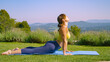 Young woman stretching in upward facing dog pose during yoga in a serene garden