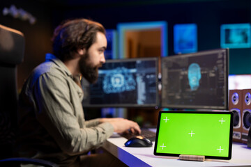 Poster - focus on green screen device next to man in blurry background updating artificial intelligence neura