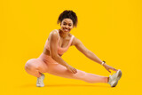 Fototapeta Tulipany - Energetic black woman doing a fitness side lunge
