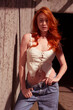 Beautiful red-haired girl with freckles in a fashionable outfit on a gray wall.