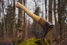 An Old Ax Stuck In A Green Mossy Stump