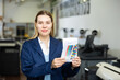 Portrait of positive woman printing office worker holding colour test page for printer.