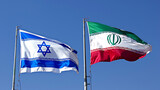 Fototapeta  - An image featuring the flags of Israel and Iran side by side, gently fluttering in the breeze against a backdrop of clear blue sky.