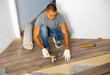 Man laying parquet on floor during home improvement works in apartment.