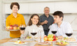 © JackF - Smiling young guy with girlfriend visiting parents. Young couple sitting with glasses of wine at family holiday table