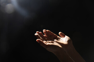 Wall Mural - Religion. Woman with open palms praying on black background, closeup. Space for text